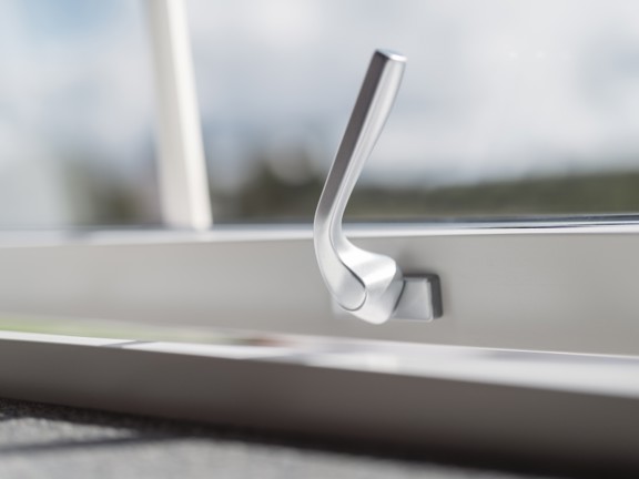 Silvrigt fönsterhandtag på ett vitt Elitfönster