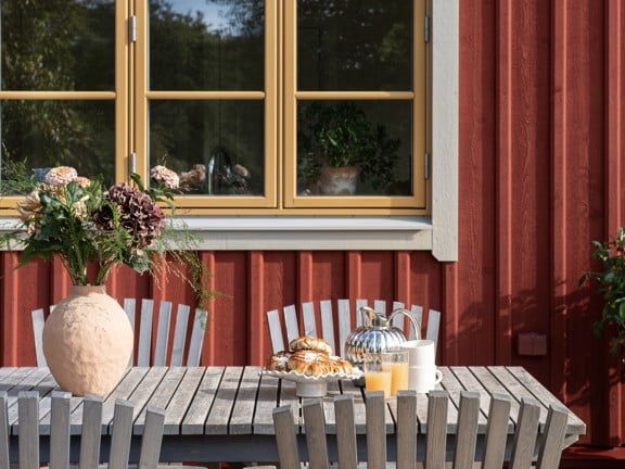 Ockragula fönster på ett rött trähus